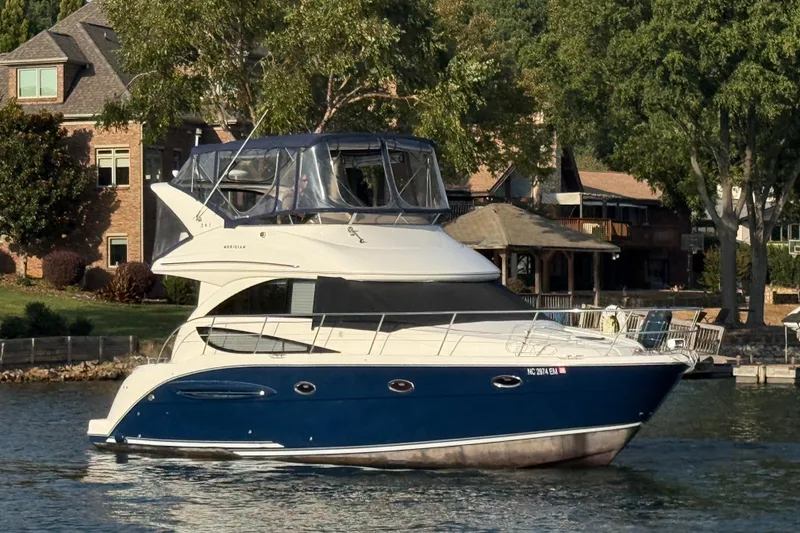 Slide: The Image of 2011 Meridian 341 Sedan yacht on a serene lake near waterfront homes. - 4
