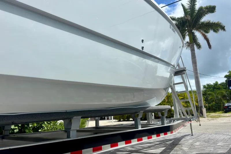 Slide: The Image of 2024 World Cat 325 CC boat on trailer, palm trees in background. - 12