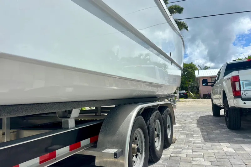 Slide: The Image of 2024 World Cat 325 CC boat on trailer, parked beside a white truck. - 13