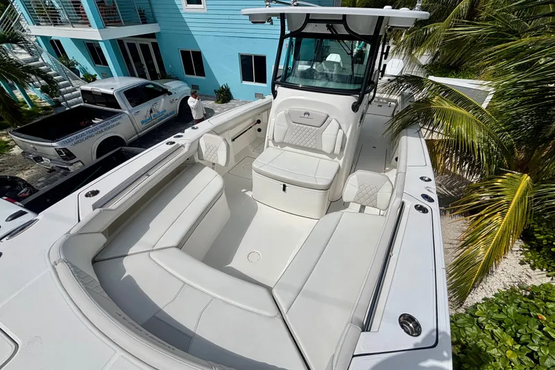 Slide: The Image of 2024 World Cat 325 CC boat with spacious seating, docked near a blue building and palm trees. - 21
