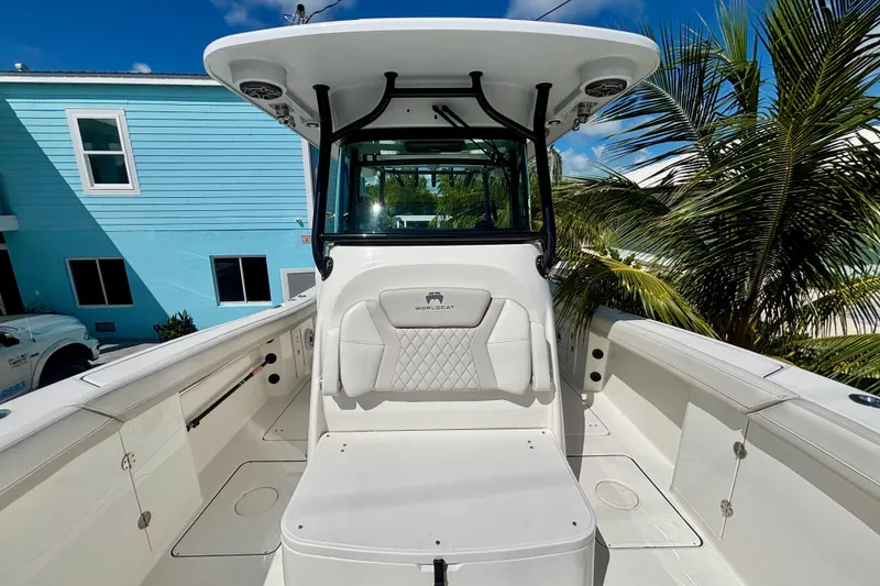 Slide: The Image of 2024 World Cat 325 CC boat interior with seating, palm trees, and blue sky background. - 30
