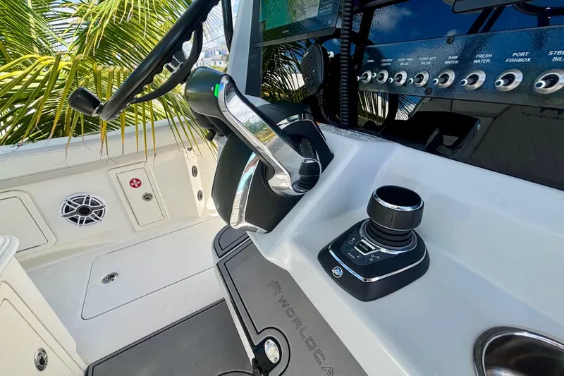 Slide: The Image of 2024 World Cat 325 CC boat helm with controls and dashboard, surrounded by tropical foliage. - 41