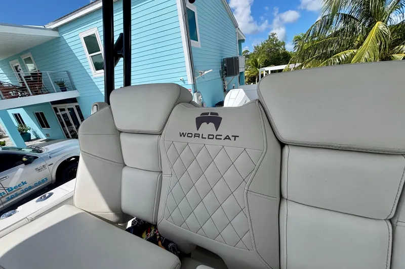 Slide: The Image of 2024 World Cat 325 CC boat seat with logo, set against a coastal house backdrop. - 48