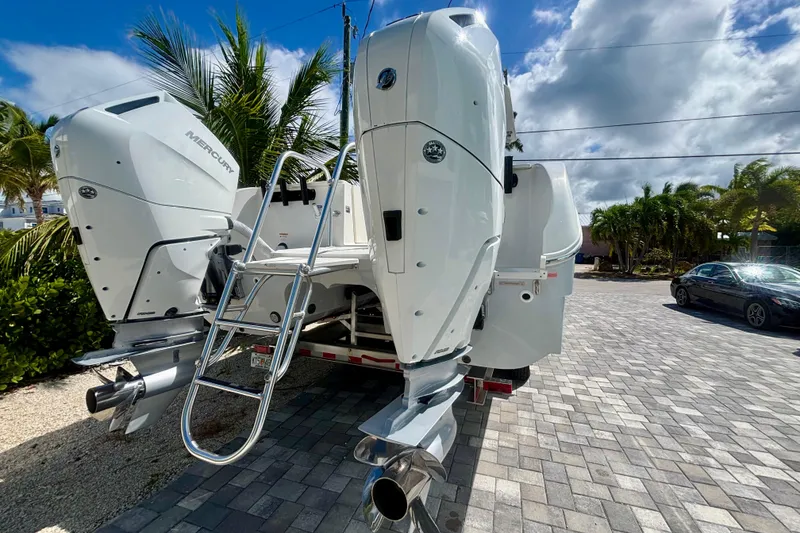 Slide: The Image of 2024 World Cat 325 CC boat with dual Mercury outboard engines and ladder, parked on a paved driveway. - 5