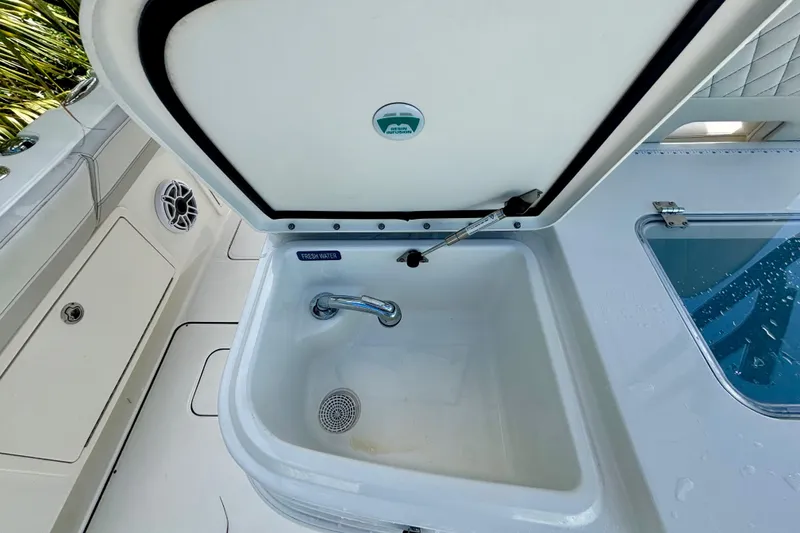 Slide: The Image of 2024 World Cat 325 CC boat sink with fresh water faucet and storage compartment. - 53