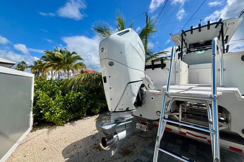 Slide: The Image of 2024 World Cat 325 CC boat with Mercury outboard engine and ladder, set against a tropical backdrop. - 7