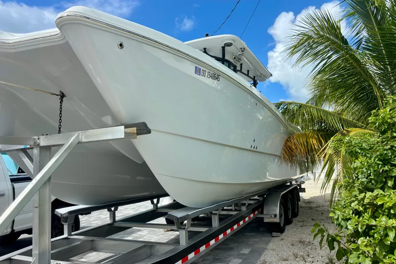 Slide: The Image of 2024 World Cat 325 CC boat on trailer, surrounded by palm trees under a clear blue sky. - 9