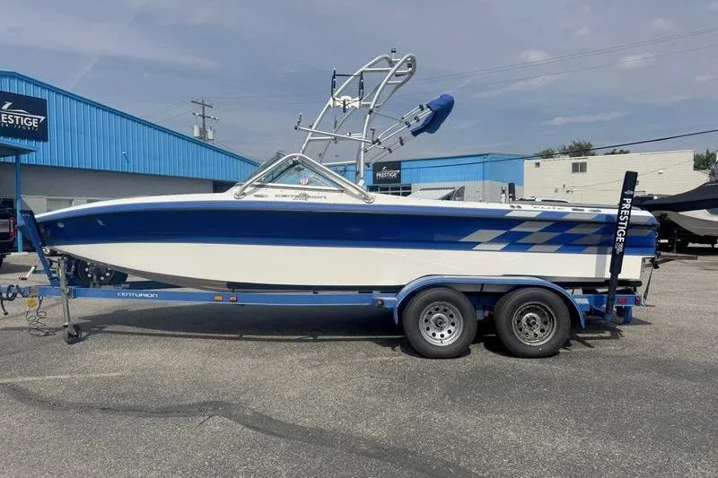 Slide: The Image of 2004 Centurion ELITE V boat on trailer, blue and white design, parked outside dealership. - 4