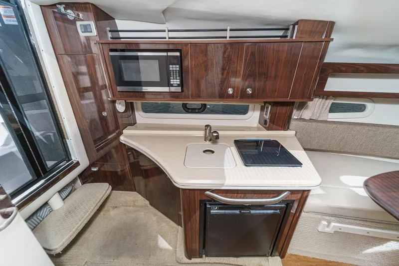 Slide: The Image of 2016 Sea Ray 280 Sundancer interior kitchen with microwave, sink, and mini-fridge. - 26