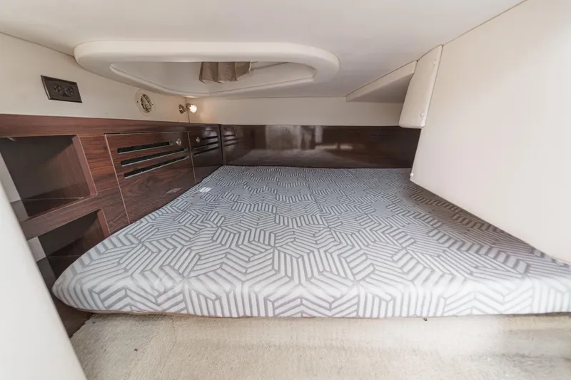 Slide: The Image of 2016 Sea Ray 280 Sundancer cabin interior with patterned mattress and wooden accents. - 28