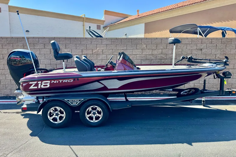 The Image of 2023 Nitro Z18 boat with trailer, parked outdoors, featuring a sleek maroon and silver design. - 0