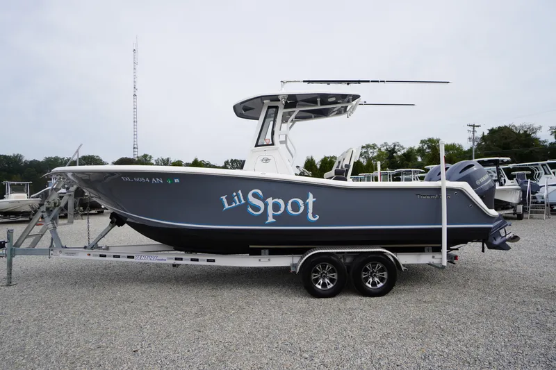 The Image of 2021 Tidewater 256 CC Adventure boat on trailer, side view, gray hull, "Lil Spot" text. - 0