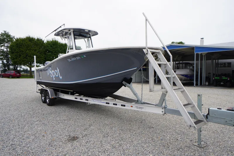 Slide: The Image of 2021 Tidewater 256 CC Adventure boat on trailer, parked outdoors. - 2
