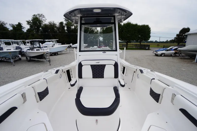 Slide: The Image of 2021 Tidewater 256 CC Adventure boat interior with seating and console, parked outdoors. - 23