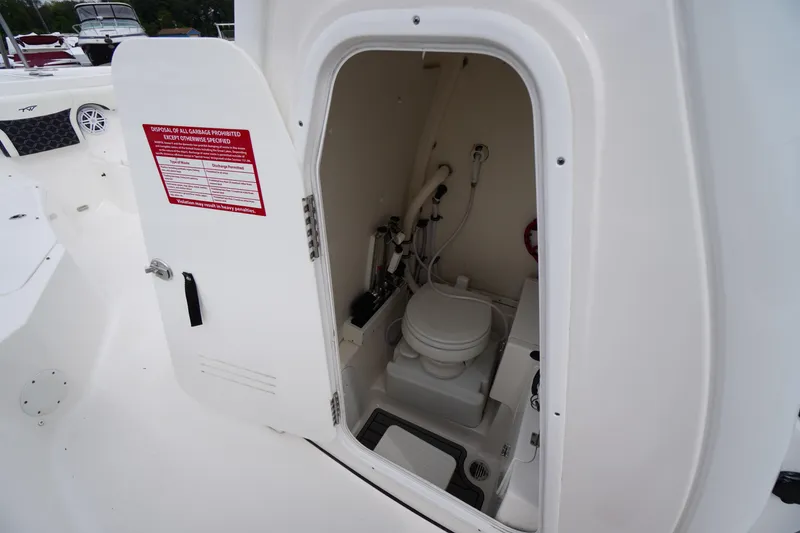 Slide: The Image of 2021 Tidewater 256 CC Adventure boat interior with open door to compact marine toilet. - 27