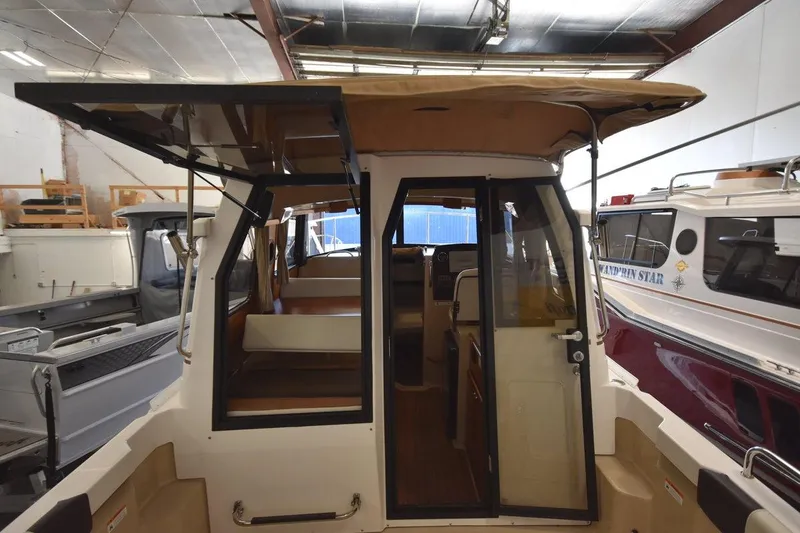 Slide: The Image of 2018 Ranger Tugs R-23 boat interior with open cabin door in a storage facility. - 13
