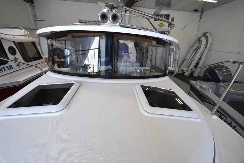 Slide: The Image of 2018 Ranger Tugs R-23 boat in showroom, showcasing sleek design and windows. - 17