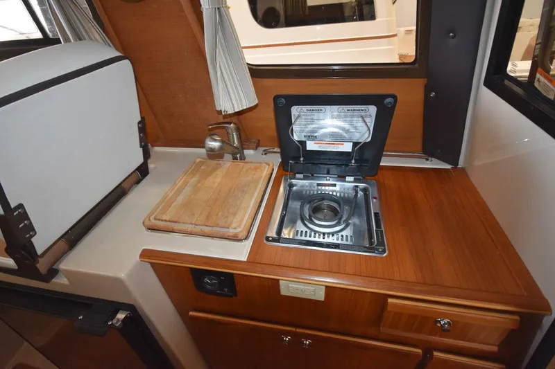 Slide: The Image of Compact kitchen area in a 2018 Ranger Tugs R-23 boat with stove and cutting board. - 27