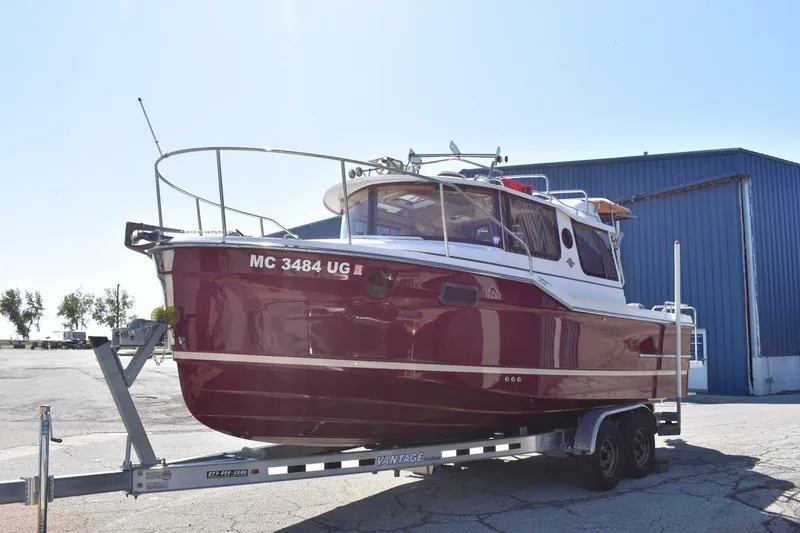 Slide: The Image of 2018 Ranger Tugs R-23 boat on trailer, red hull, parked near blue building. - 4