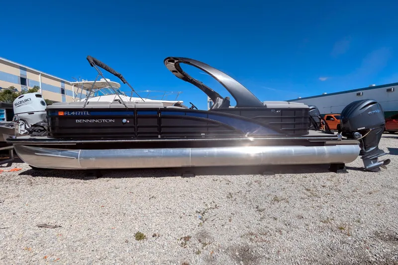 Slide: The Image of 2023 Bennington R 27 RSRAX2 pontoon boat with Suzuki outboard motor on gravel. - 6