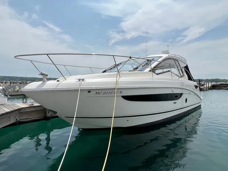 Slide: The Image of 2019 Sea Ray Sundancer 350 Coupe docked on clear water under a partly cloudy sky. - 2