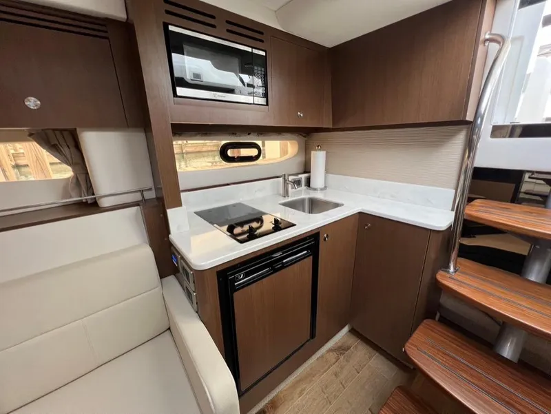 Slide: The Image of 2019 Sea Ray Sundancer 350 Coupe kitchen with modern appliances and wooden cabinetry. - 26