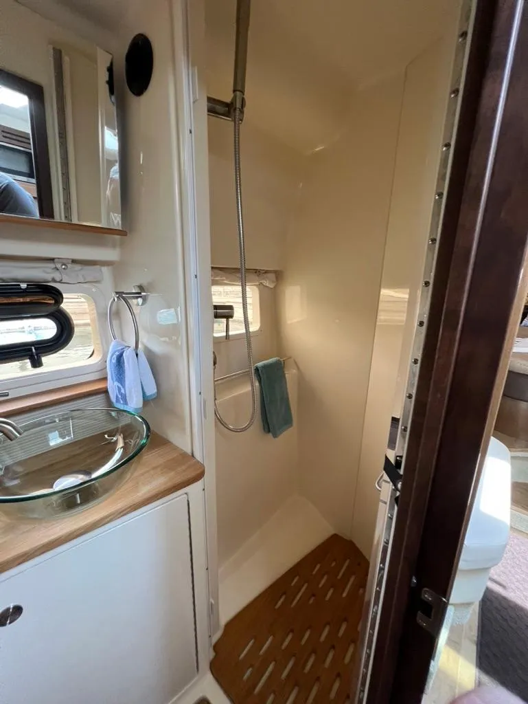 Slide: The Image of 2019 Sea Ray Sundancer 350 Coupe bathroom with shower, sink, and wooden accents. - 31