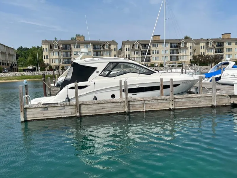 Slide: The Image of 2019 Sea Ray Sundancer 350 Coupe docked at marina, with waterfront buildings in background. - 8