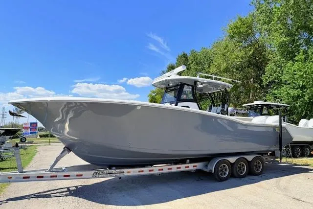 Slide: The Image of 2023 Tidewater 320 CC Adventure boat on a trailer, parked outdoors under a clear blue sky. - 1