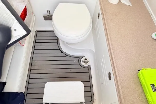 Slide: The Image of 2023 Tidewater 320 CC Adventure boat bathroom with toilet and non-slip flooring. - 16