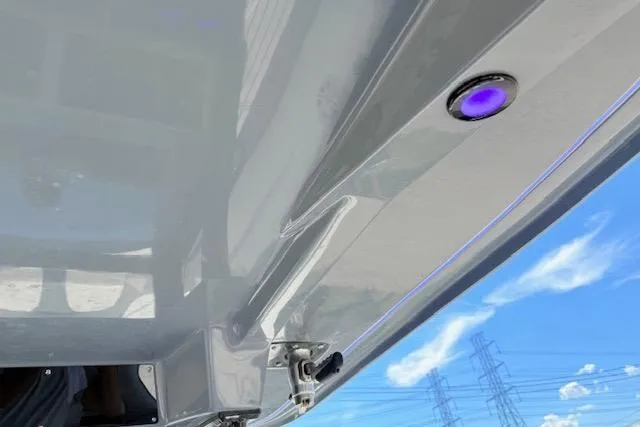 Slide: The Image of 2023 Tidewater 320 CC Adventure boat hull with blue LED light against sky. - 20