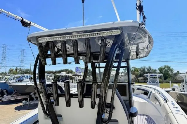 Slide: The Image of 2023 Tidewater 320 CC Adventure boat with rod holders and T-top, docked under clear blue sky. - 7