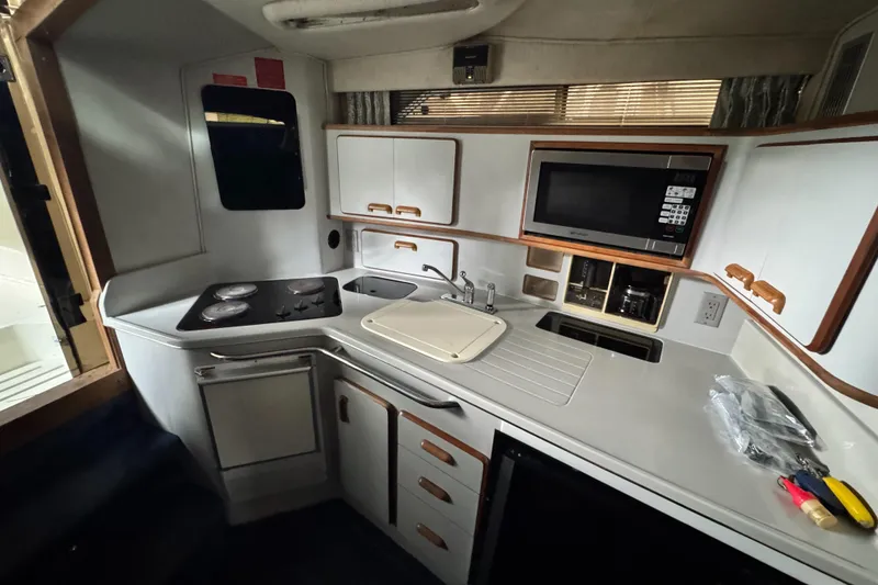 Slide: The Image of 1990 Sea Ray 350 Express Cruiser kitchen with stove, microwave, and sink. - 9