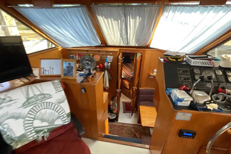 Slide: The Image of 1989 Jefferson 37 Sundeck interior with red and white seating, helm station, and marina view. - 25