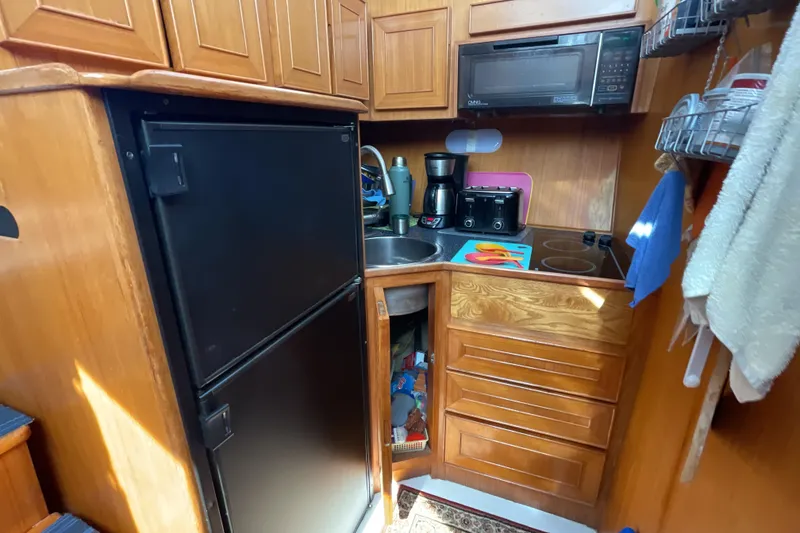 Slide: The Image of Compact kitchen in 1989 Jefferson 37 Sundeck boat with wooden cabinets and modern appliances. - 36