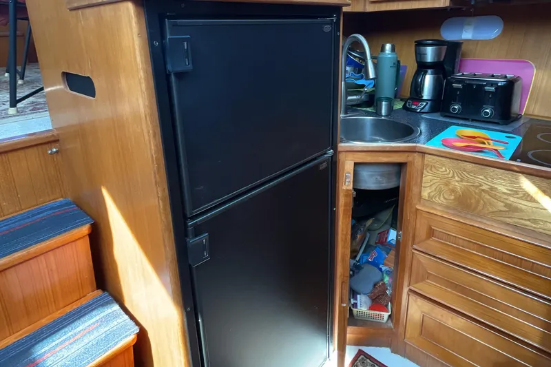 Slide: The Image of Compact kitchen in 1989 Jefferson 37 Sundeck boat with wooden cabinets and modern appliances. - 37
