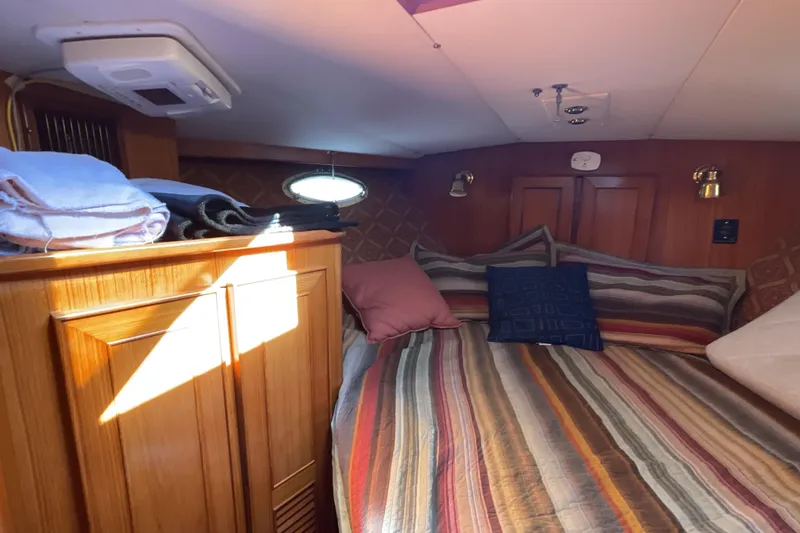 Slide: The Image of Cozy cabin interior of 1989 Jefferson 37 Sundeck with striped bedding and porthole window. - 41