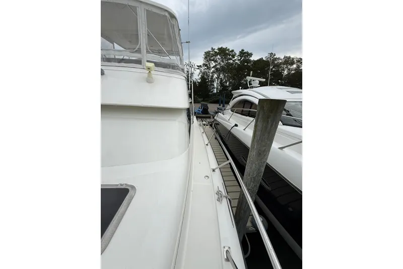 Slide: The Image of 1991 Tiara Yachts 4300 Convertible docked beside another boat, overcast sky. - 14