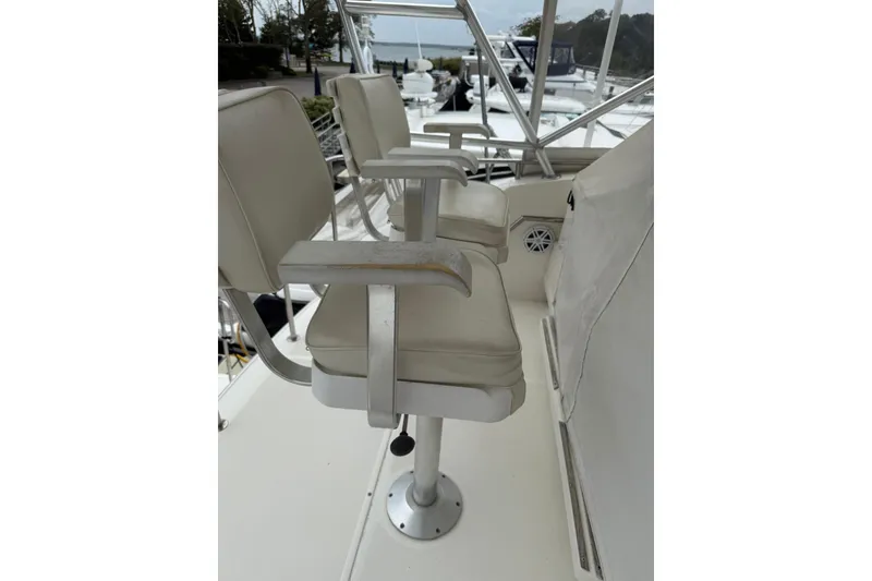 Slide: The Image of 1991 Tiara Yachts 4300 Convertible helm seats with white cushions and metal frames. - 17