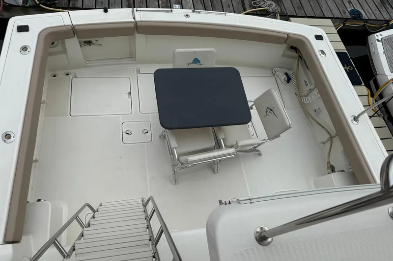 Slide: The Image of 1991 Tiara Yachts 4300 Convertible deck with table and chairs, docked at marina. - 4