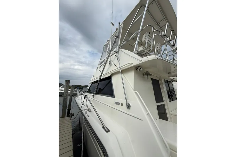 Slide: The Image of 1991 Tiara Yachts 4300 Convertible docked, showcasing sleek design and upper deck seating. - 48