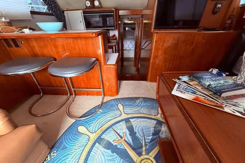 Slide: The Image of 1991 Tiara Yachts 4300 Convertible interior with wooden cabinetry, stools, and nautical-themed decor. - 49
