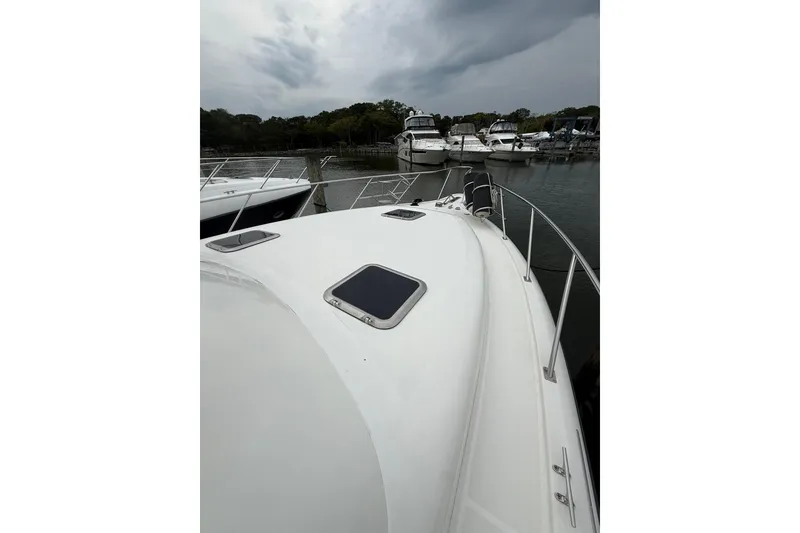 Slide: The Image of 1991 Tiara Yachts 4300 Convertible docked, showcasing sleek deck design under cloudy skies. - 56