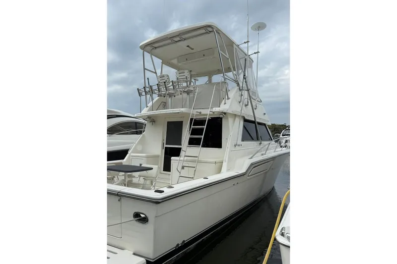 Slide: The Image of 1991 Tiara Yachts 4300 Convertible, white exterior, docked at marina under cloudy sky. - 61