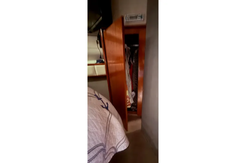 Slide: The Image of Interior of 1991 Tiara Yachts 4300 Convertible showing open wooden closet and bedding. - 64