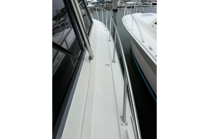 Slide: The Image of 1991 Tiara Yachts 4300 Convertible, side deck view with railing in marina. - 75