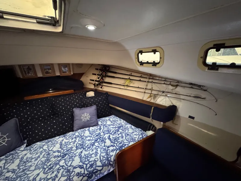 Slide: The Image of 1999 Mainship Pilot 30 Sedan cabin interior with fishing rods and nautical-themed decor. - 15