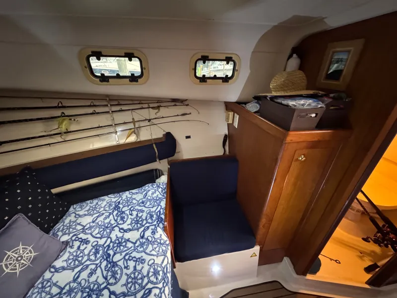 Slide: The Image of 1999 Mainship Pilot 30 Sedan cabin interior with fishing rods and nautical decor. - 17