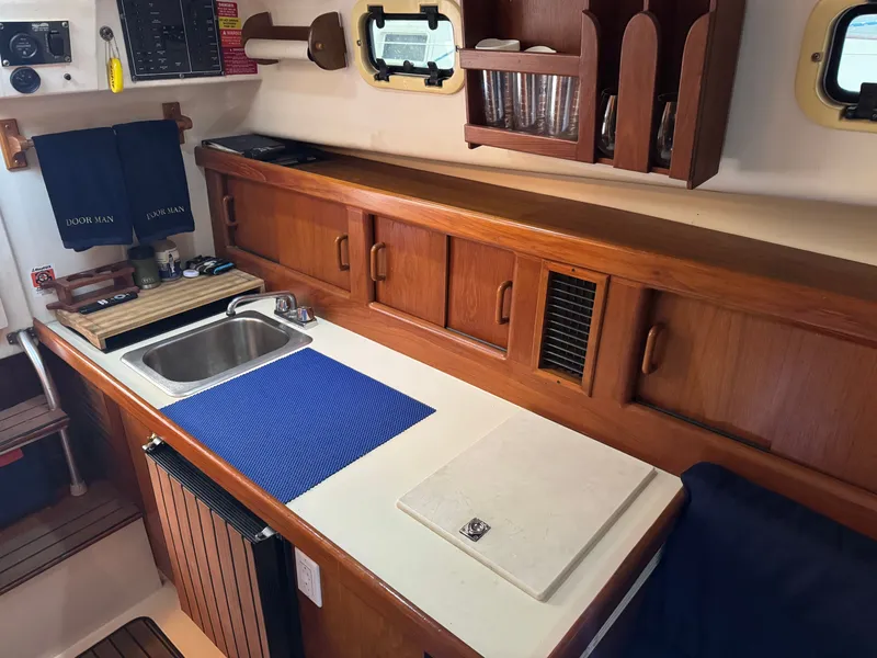 Slide: The Image of 1999 Mainship Pilot 30 Sedan interior with wooden cabinetry, sink, and countertop. - 19