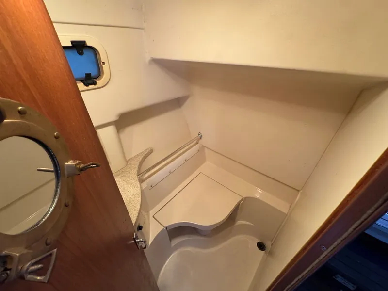 Slide: The Image of 1999 Mainship Pilot 30 Sedan bathroom with porthole and compact shower area. - 24